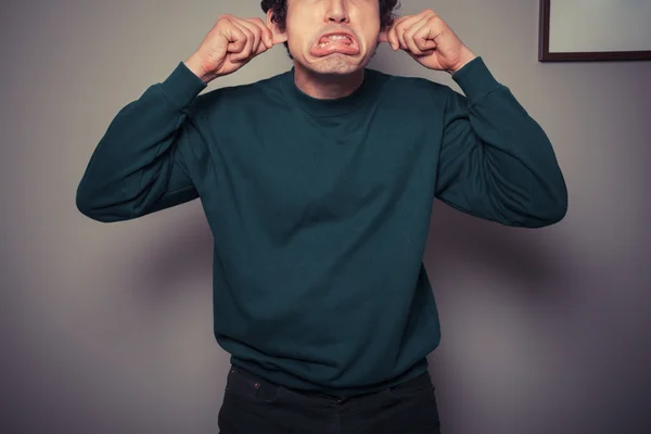 Giovane uomo che tira facce stupide — Foto Stock