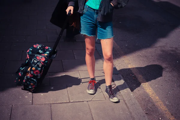 Young woman standing in the street with a suitcase — Stock Photo, Image