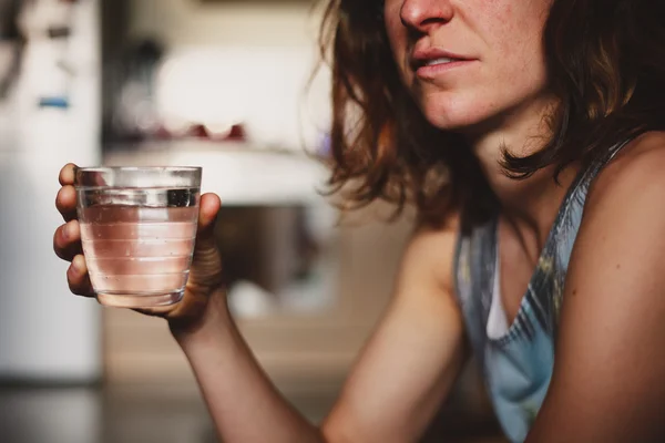 Mujer joven bebiendo agua en casa — Foto de Stock