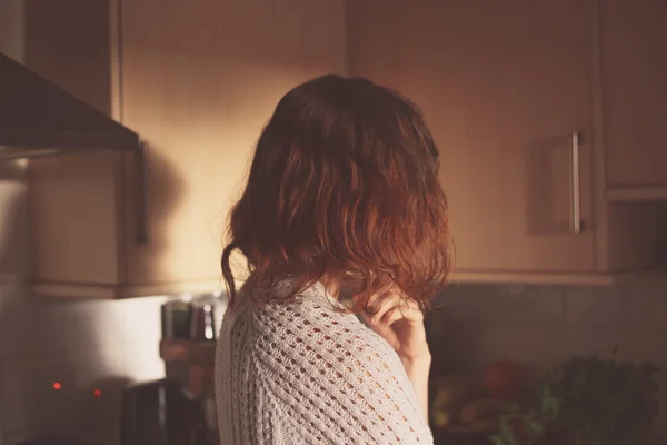 Mujer joven de pie en su cocina y pensando — Foto de Stock