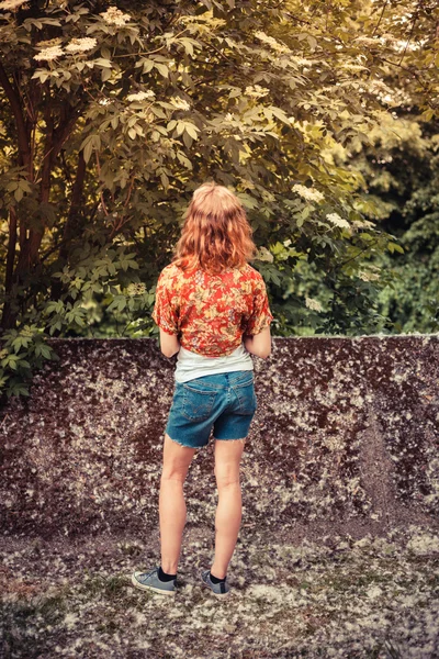 Jeune femme debout dehors entourée d'arbres en fleurs — Photo