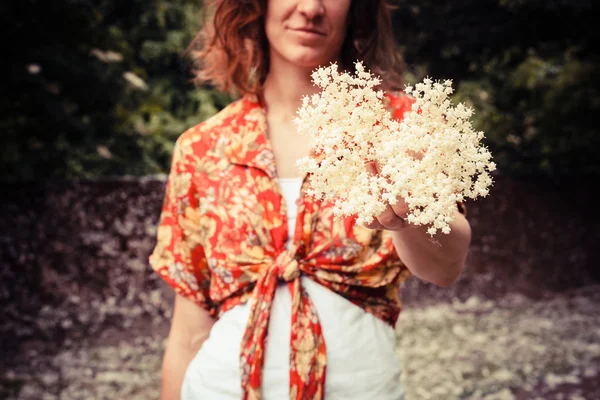 Młoda kobieta trzymając kilka elderflowers — Zdjęcie stockowe