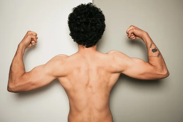 Rear view of shirtless man against dual colored background — Stock Photo, Image