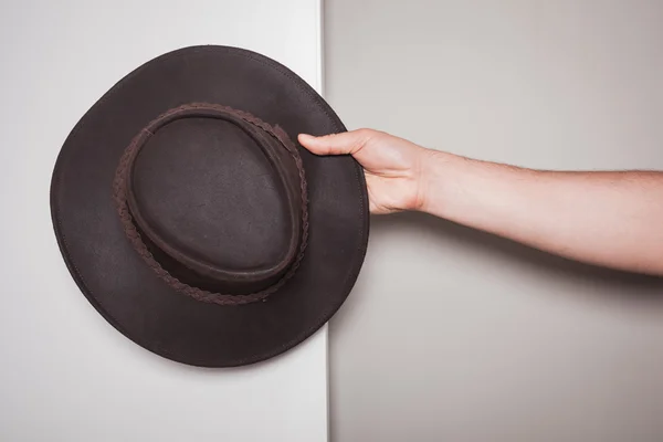 Mão segurando um chapéu de cowboy contra fundo de cor dupla — Fotografia de Stock