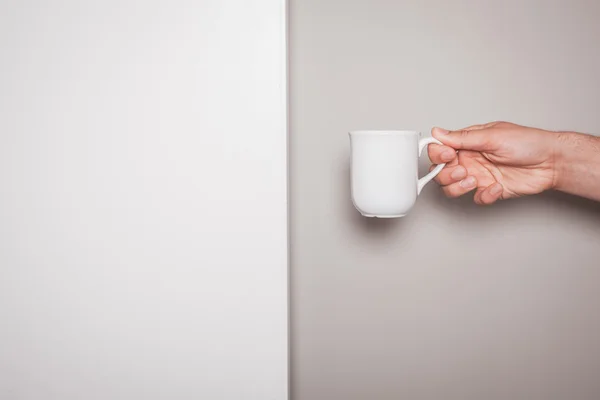 Mão segurando uma xícara contra fundo de cor dupla — Fotografia de Stock