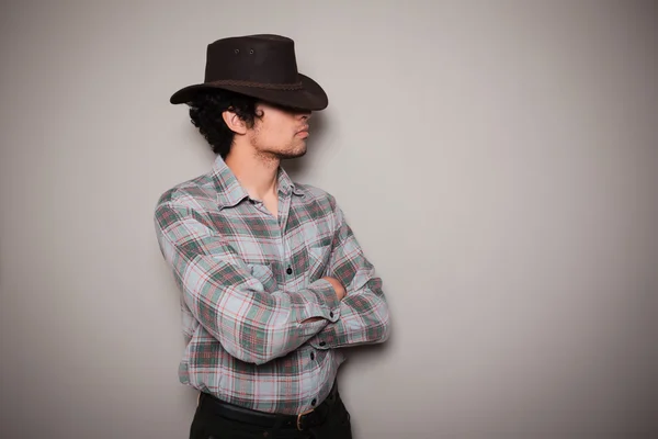Jonge cowboy in plaid shirt tegen een groene muur — Stockfoto