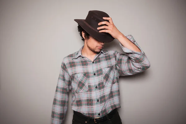 Jovem cowboy em camisa xadrez contra uma parede verde — Fotografia de Stock