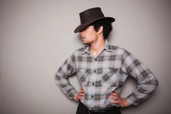 Jovem cowboy em camisa xadrez contra uma parede verde — Fotografia de Stock
