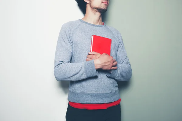 Young man with red book against split colored background — Stock Photo, Image