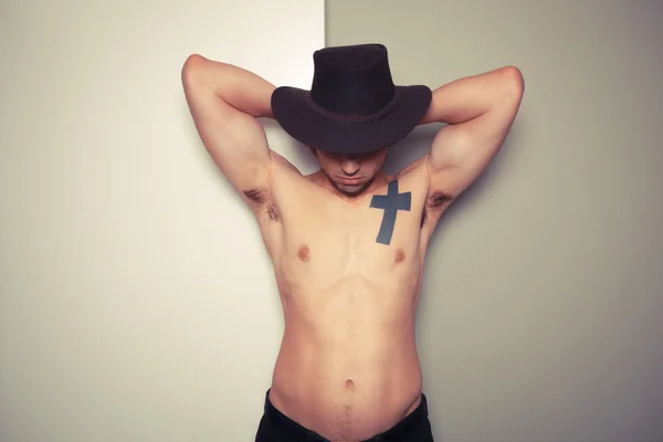 Shirtless young cowboy against dual colored background — Stock Photo, Image