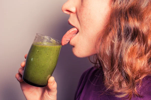 Mujer joven bebiendo batido verde — Foto de Stock