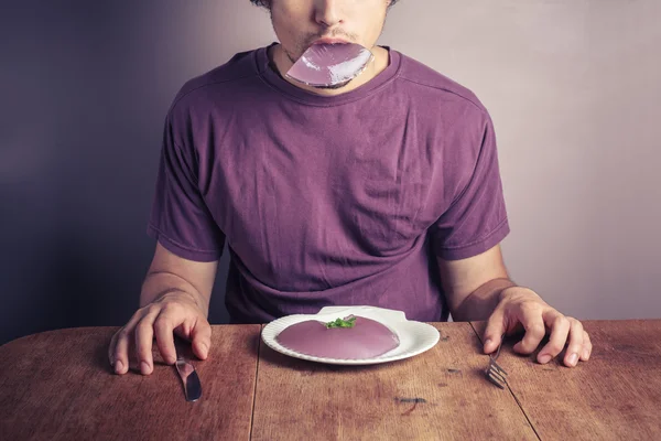 Young man eating purple pudding — Stock Photo, Image