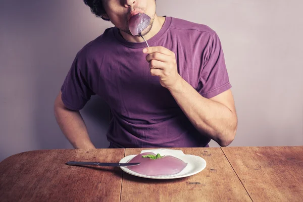 Young man eating purple pudding — Stock Photo, Image