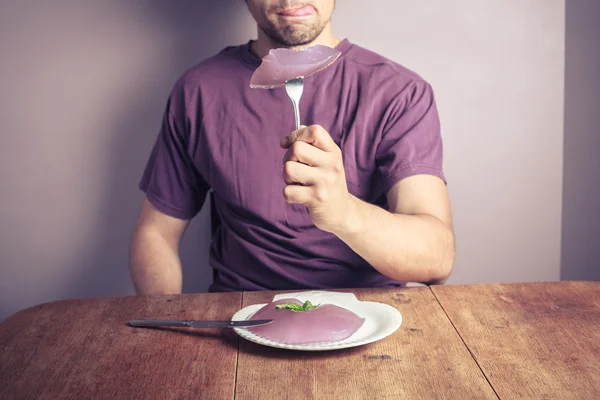 Young man eating purple pudding — Stock Photo, Image