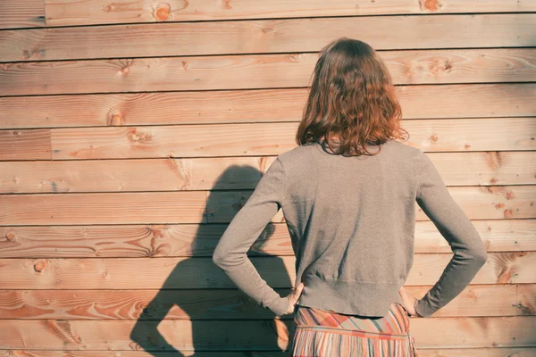 Young woman standing outside wooden cabin — Stock Photo, Image