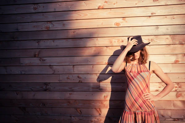 Young woman wearing cowboy hat by a cabin — Stock Photo, Image