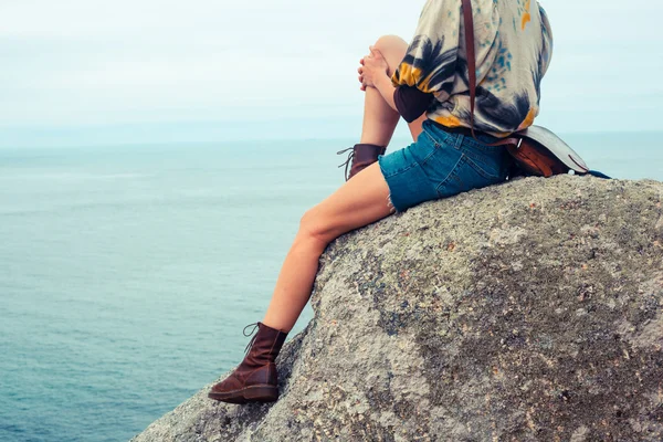 Νεαρή γυναίκα που κάθεται πάνω σε ένα βράχο δίπλα στη θάλασσα — Φωτογραφία Αρχείου