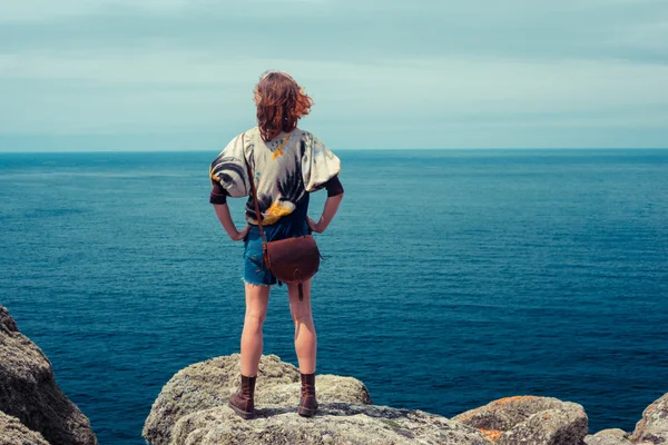 Junge Frau steht auf einem Felsen am Meer — Stockfoto