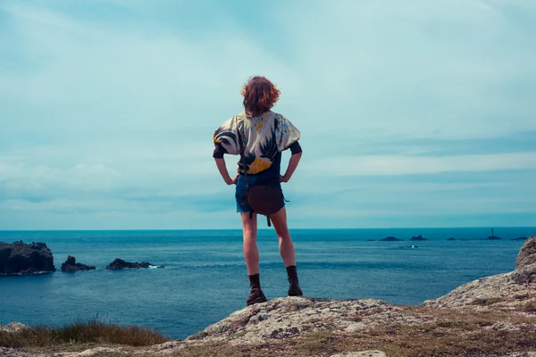 Ung kvinna som står på en klippa vid havet — Stockfoto