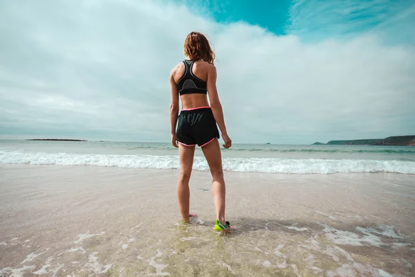 Sportovní mladá žena chůze na pláž — Stock fotografie