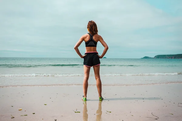 Ajuste jovem mulher de pé na praia — Fotografia de Stock