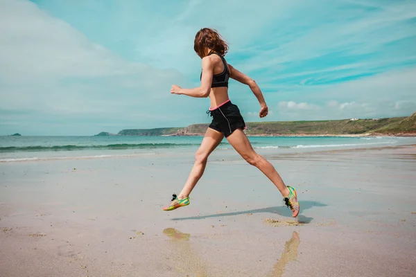 Młoda kobieta biegająca po plaży — Zdjęcie stockowe