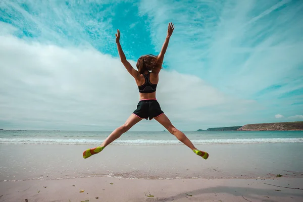 Giovane donna che fa salti stellari sulla spiaggia — Foto Stock