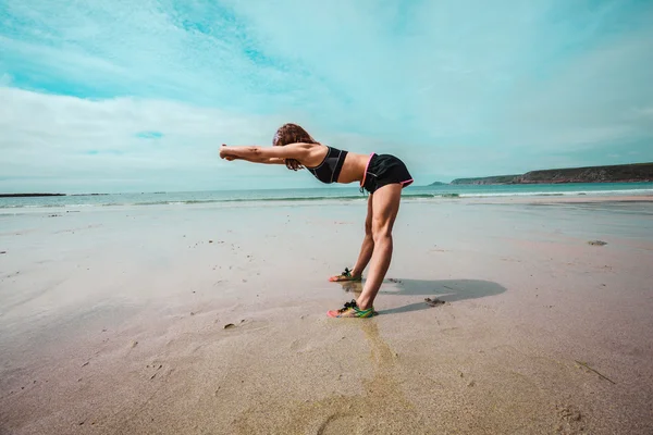 Young athletic woman stretching on the beach — Stock Photo, Image