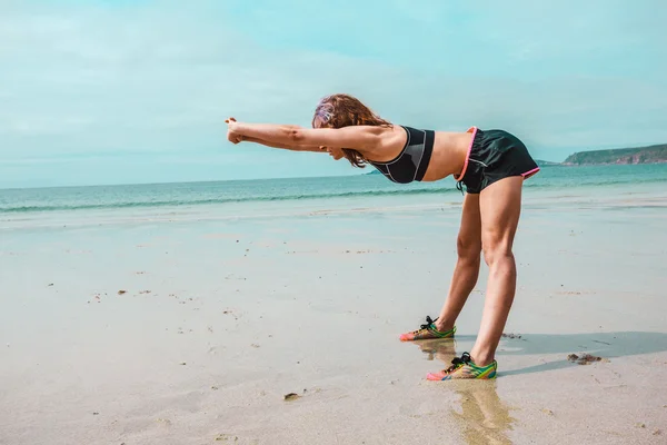 Młoda kobieta lekkoatletycznego rozciąga się na plaży — Zdjęcie stockowe