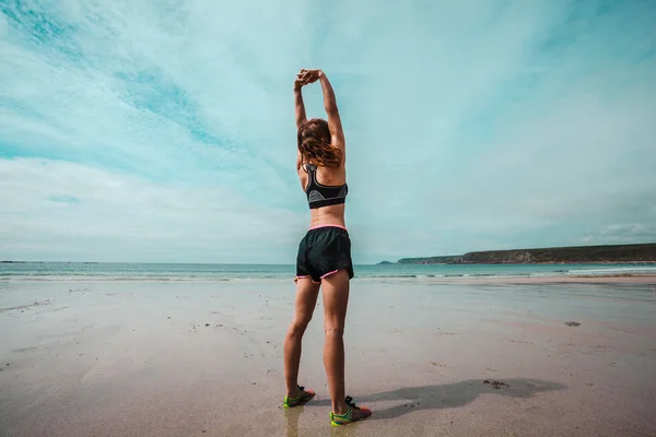 Giovane donna atletica che si estende sulla spiaggia — Foto Stock