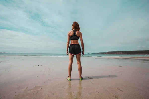 年轻运动的女人站在沙滩上 — 图库照片