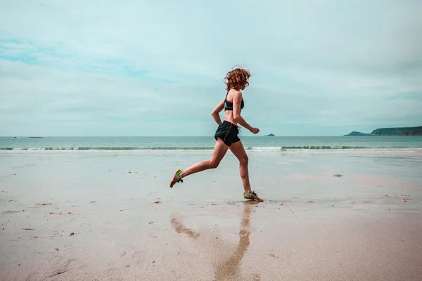 Mujer joven corriendo en la playa —  Fotos de Stock