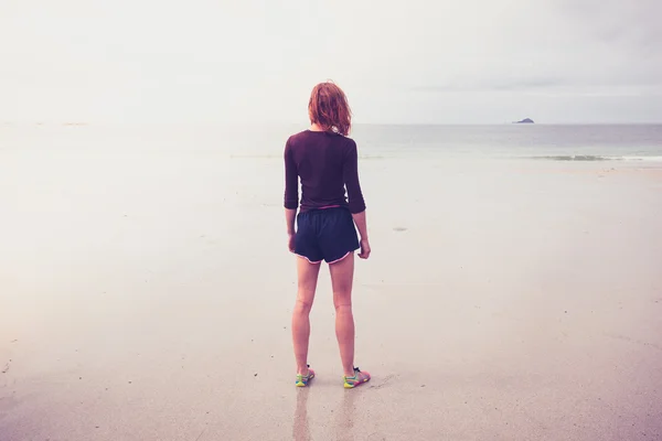 Mujer joven de pie junto al mar — Foto de Stock