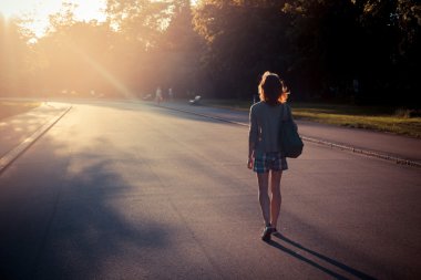 gün batımına doğru bir parkta yürüyen kadın