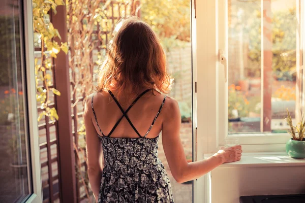 Mujer de pie en la puerta al amanecer — Foto de Stock