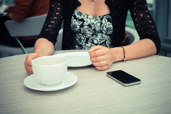 Женщина пьет кофе, ожидая телефонного звонка — стоковое фото