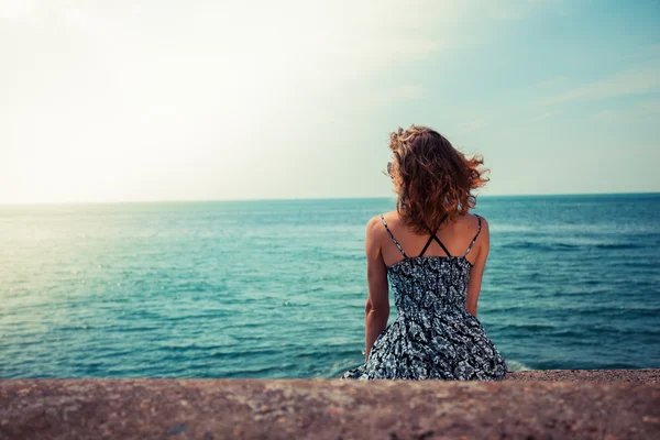 Ung kvinna sitter vid havet — Stockfoto