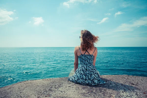 Young woman sitting by the ocean — Stock Photo, Image