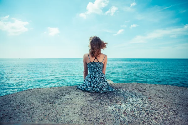 Ung kvinna sitter vid havet — Stockfoto