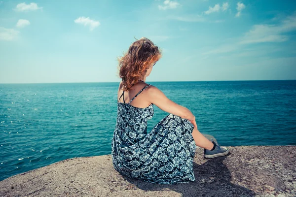 Giovane donna seduta vicino all'oceano — Foto Stock