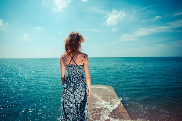 Jovem de vestido em pé junto ao oceano — Fotografia de Stock