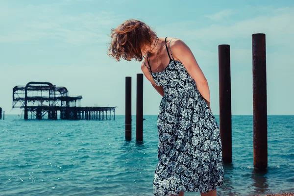 Giovane donna in piedi vicino all'oceano con il vecchio molo — Foto Stock