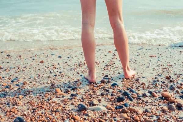 Le gambe di una giovane donna in piedi sulla spiaggia — Foto Stock