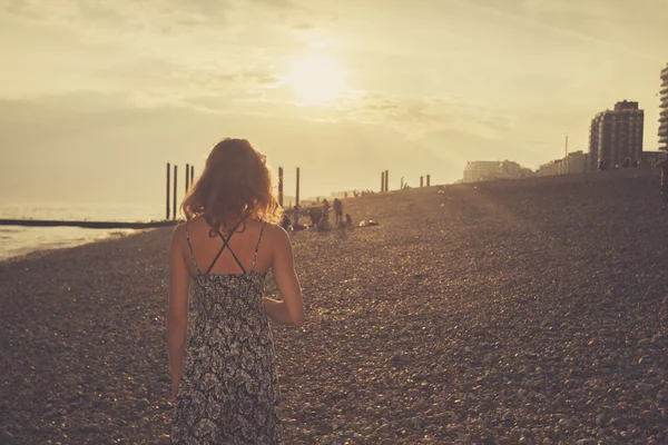 Νεαρή γυναίκα στην παραλία το ηλιοβασίλεμα — Φωτογραφία Αρχείου