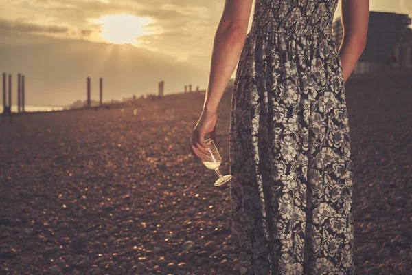 Mladá žena na pláži se sklenicí vína — Stock fotografie
