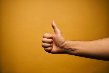 The hand of a young man ios gesturing against a yellow background