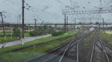 4k, demiryoluna giden bir trenin ıslak ön camından görüş.