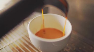 4k, espresso kahve makinesinden beyaz bir fincana dökülüyor, ağır çekimde.