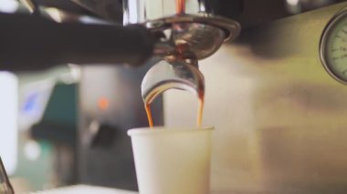 4K, espresso kahve makinesinden beyaz kağıt bardağa dökülüyor, yavaş çekimde.