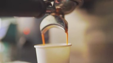 4K, espresso kahve makinesinden beyaz kağıt bardağa dökülüyor, yavaş çekimde.
